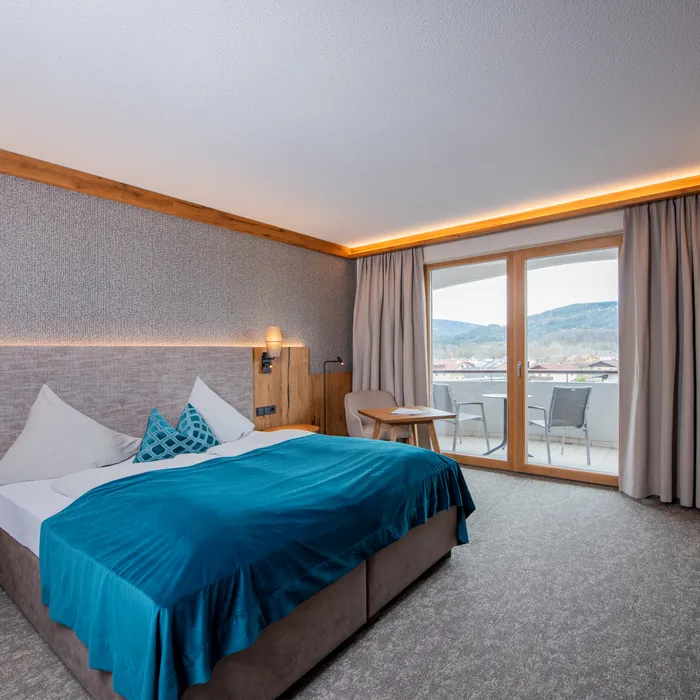 Camera d'hotel moderna con letto matrimoniale, vista balcone e paesaggio montano